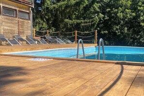 A wooden deck with a swimming pool, lounge chairs, and a rope barrier. - Carlsbad Wellness & Camping Resort (Březová)