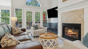 Un salon avec une cheminée, un canapé en cuir et une table basse ronde.