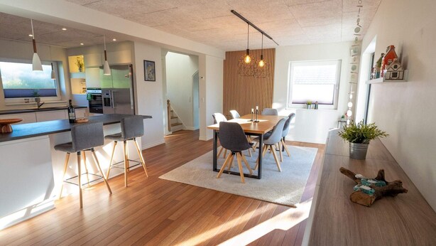 Une cuisine moderne avec un coin repas, un plancher en bois et des luminaires suspendus.