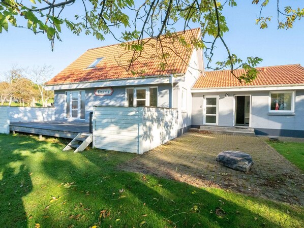 Ein zweistöckiges Haus mit Ziegeldach, einer Veranda und einem gepflasterten Auffahrt.