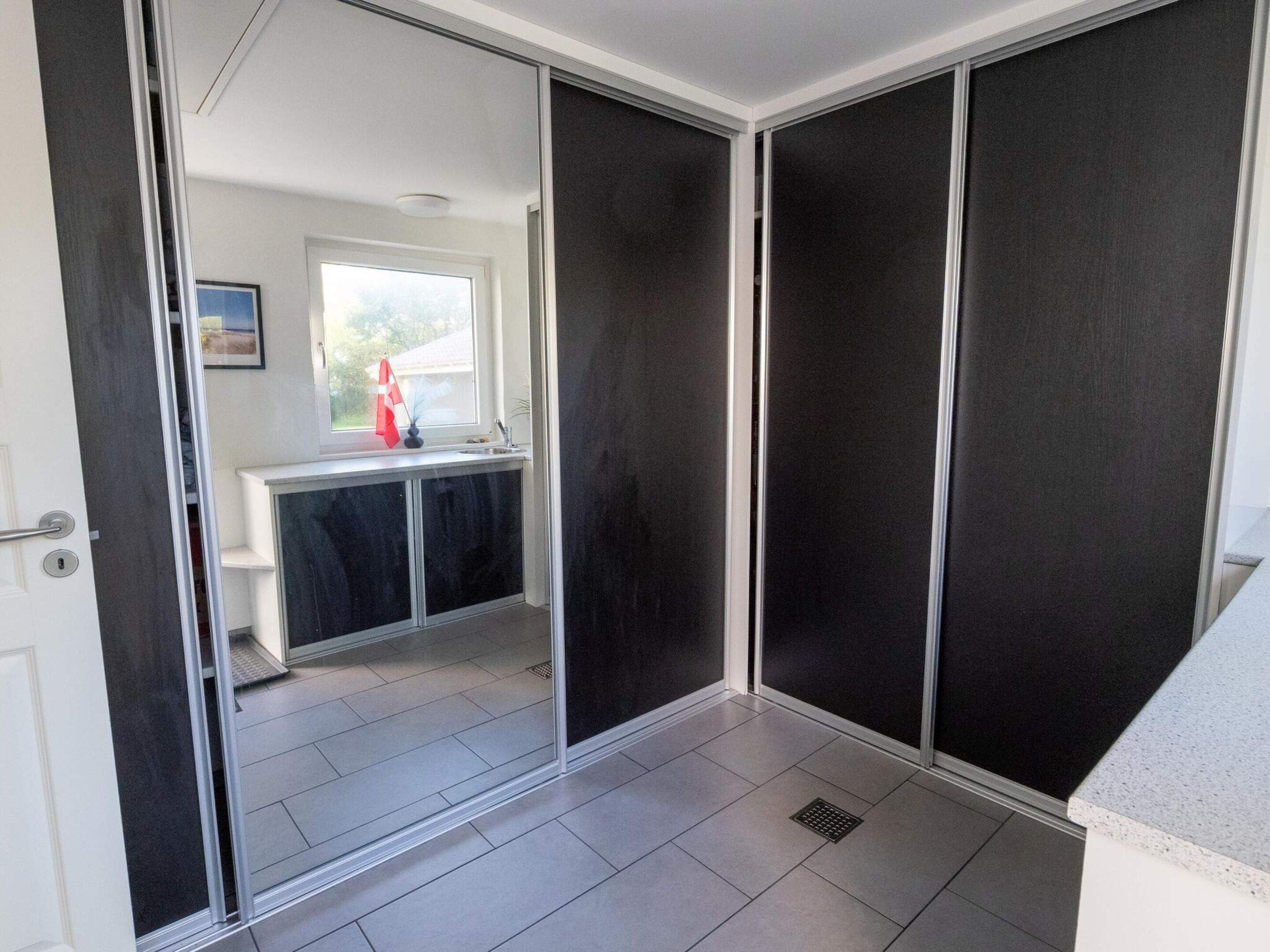 A modern interior with a sliding door leading to a bathroom, a window with a towel, and a sink.