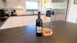 Une cuisine moderne avec une bouteille de vin posée sur le comptoir, une machine à café et un réfrigérateur.