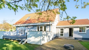 Une maison à deux étages, avec un toit en tuiles, un porche à l’avant et une allée pavée.