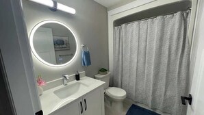 A bathroom with a white sink, mirror, and toilet.