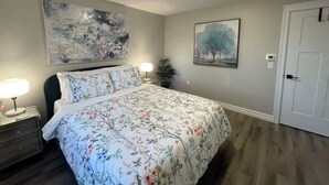 A bedroom with a bed, nightstands, a lamp, and two paintings on the walls.
