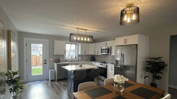 A modern kitchen with a central island, stainless steel appliances, and pendant lighting.