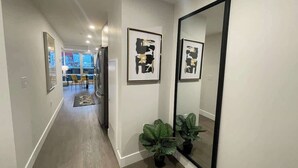 A hallway with a large mirror, framed artwork, and potted plants. - Downtown, bright & cozy 1 BR with 6 appliances (Halifax)