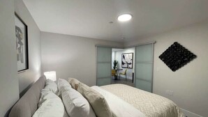 A modern bedroom with a bed, a sofa, a desk, and a wall-mounted artwork. - Downtown, bright & cozy 1 BR with 6 appliances (Halifax)