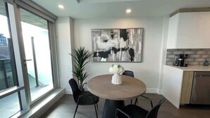 A modern dining area with a round table, black chairs, and a large abstract painting on the wall. - Large 1 BR downtown with lots of sunlight (Halifax)