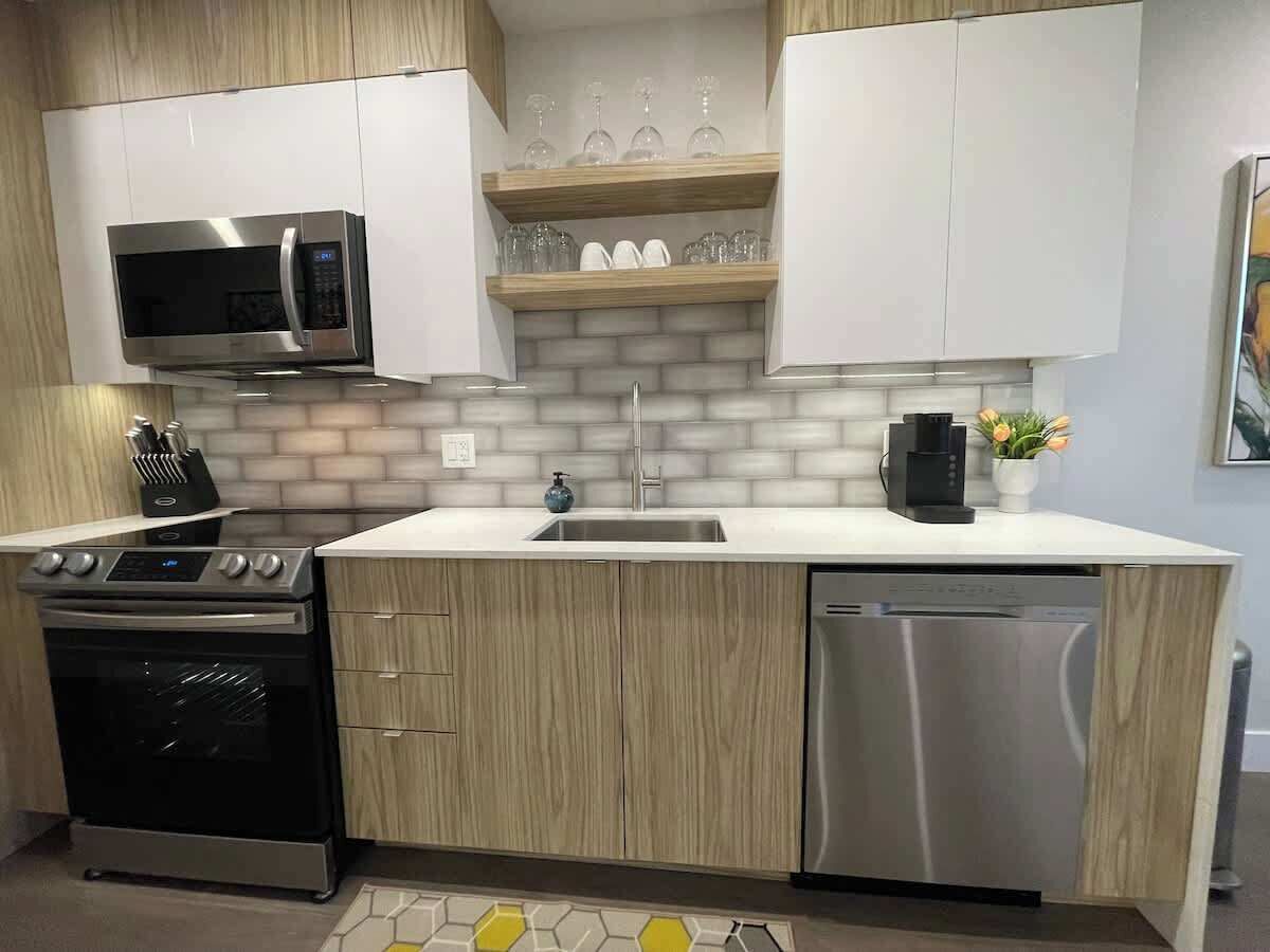 A modern kitchen with stainless steel appliances, wooden cabinets, and a white countertop.