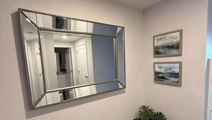 A hallway with a large mirror, two framed pictures on the wall, and a potted plant. - Downtown, Waterfront 1 Bedroom with AC and Gym (Halifax)