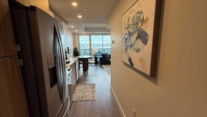 A modern kitchen with a built-in refrigerator and a dining area with a view of the city. - Downtown, Waterfront 1 Bedroom with AC and Gym (Halifax)