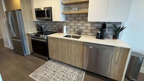 A modern kitchen with stainless steel appliances, wooden cabinetry, and a built-in microwave. - Downtown, Waterfront 1 Bedroom with AC and Gym (Halifax)