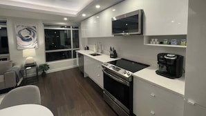 A modern kitchen with a built-in oven, a coffee maker, and a TV mounted above the counter.