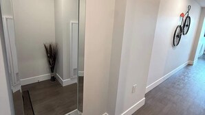 A spacious hallway with a large mirror, a broom, and a bicycle mounted on the wall.