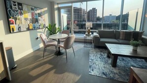 A modern living room with a large window, a round dining table, and a sofa.