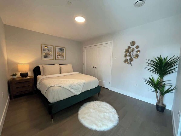 Une chambre à coucher avec un lit, des tables de chevet, une lampe, un tapis rond et une plante en pot.