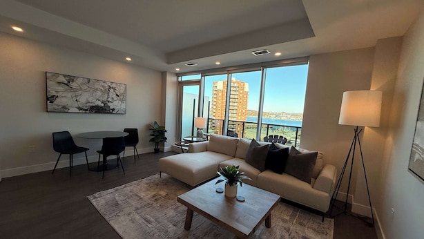 A modern living room with a sofa, coffee table, and dining area. - Waterfront penthouse 1 Bedroom with 6 appliances (Halifax)