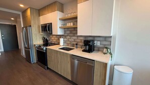 A modern kitchen with stainless steel appliances, wooden cabinets, and a built-in microwave. - Waterfront penthouse 1 Bedroom with 6 appliances (Halifax)