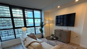 A modern living room with a large window, a sofa, a coffee table, a TV, and a cabinet.
