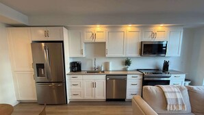 A modern kitchen with white cabinets, stainless steel appliances, and a built-in microwave.