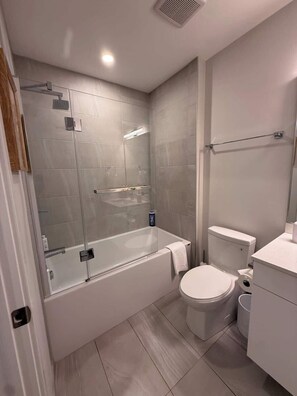 Un baño moderno con ducha envuelta en vidrio, inodoro blanco y bañera.