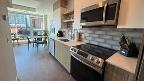 A modern kitchen with a built-in oven, microwave, and a coffee maker on the counter. - Penthouse downtown 1 Bedroom with 6 appliances (Halifax)