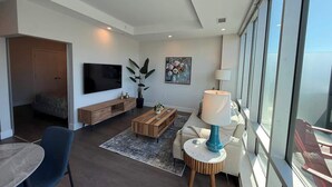 A modern living room with a flat-screen TV, wooden coffee table, and a sofa. - Penthouse downtown 1 Bedroom with 6 appliances (Halifax)