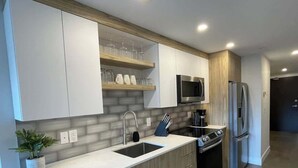 Una cocina moderna con armarios blancos, un refrigerador de acero inoxidable, un microondas y un lavavajillas.