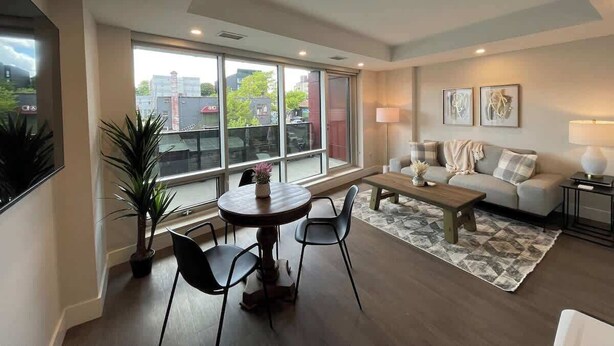 Una sala de estar moderna con comedor, ventanas grandes y un sofá.