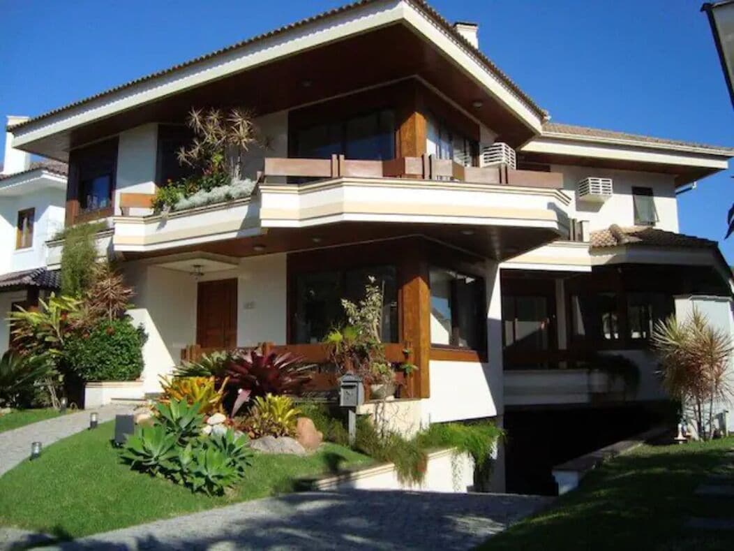 A two-story house with a balcony, a garage, and a well-maintained garden.