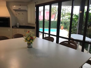 A dining area with a table, chairs, and a vase of flowers. - SPACIOUS HOUSE JURERÊ INTERNACIONAL VACANCIES FOR NEW YEAR'S EVE AND CHRISTMAS (Florianópolis)