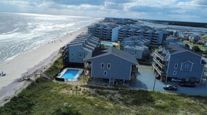 Um hotel à beira-mar com vários edifícios, uma praia e uma piscina.