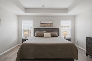 Quarto com cama, duas mesas de cabeceira, um criado-mudo e janela com persianas.