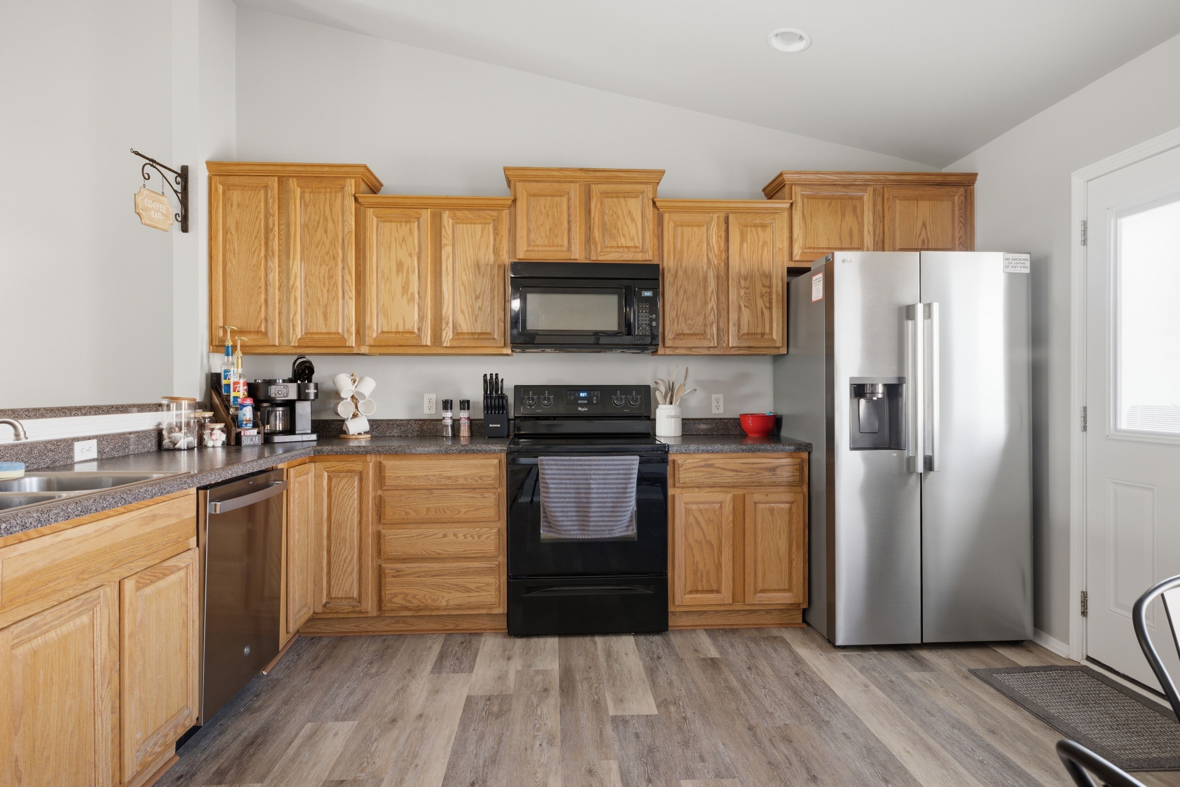 A kitchen with wooden cabinets, a stainless steel refrigerator, a microwave, and an oven.