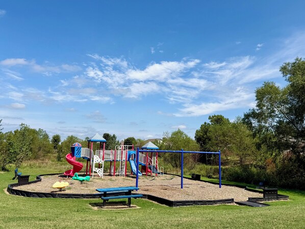 A playground with a slide, climbing structures, and a picnic table.
