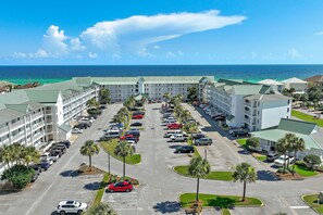 Ein Hotel mit Parkplatz, mehreren Gebäuden und Blick aufs Meer.