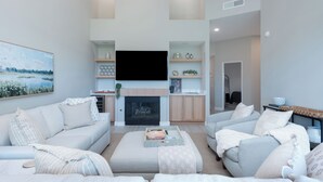 A modern living room with a fireplace, sofas, a flat-screen TV, and built-in shelving.