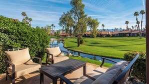 A patio with outdoor furniture, a view of a golf course, and a body of water.