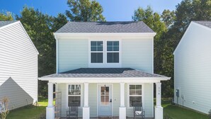 A two-story house with a front porch, a garage, and a well-maintained lawn. - Coastal Charm! 2-bedroom house in lovely Gulfport. (Gulfport)