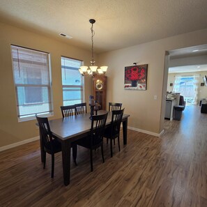 A dining area with a wooden table and chairs, a chandelier, and a painting on the wall. - Family-Friendly One-Level Home in Aloha (Beaverton)