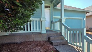 A house with a porch, steps leading to a door, and a tree in the foreground.