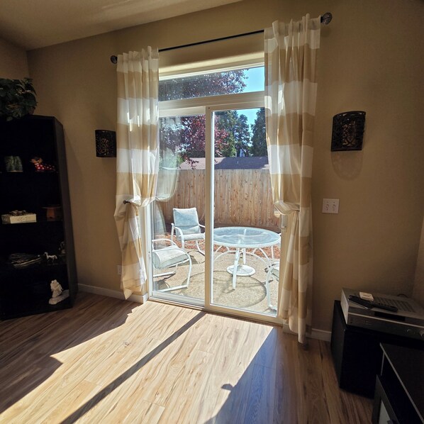 A room with a sliding glass door leading to an outdoor patio with a table and chairs.