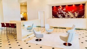 A modern lobby with a reception desk, white chairs, and a patterned floor. - “Spacious 1BR Grand Suite | Full Kitchen, Balcony & Near Universal Parks” (Orlando)
