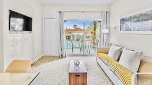 A modern living room with a sofa, a coffee table, and a TV mounted on the wall. - “Spacious 1BR Grand Suite | Full Kitchen, Balcony & Near Universal Parks” (Orlando)