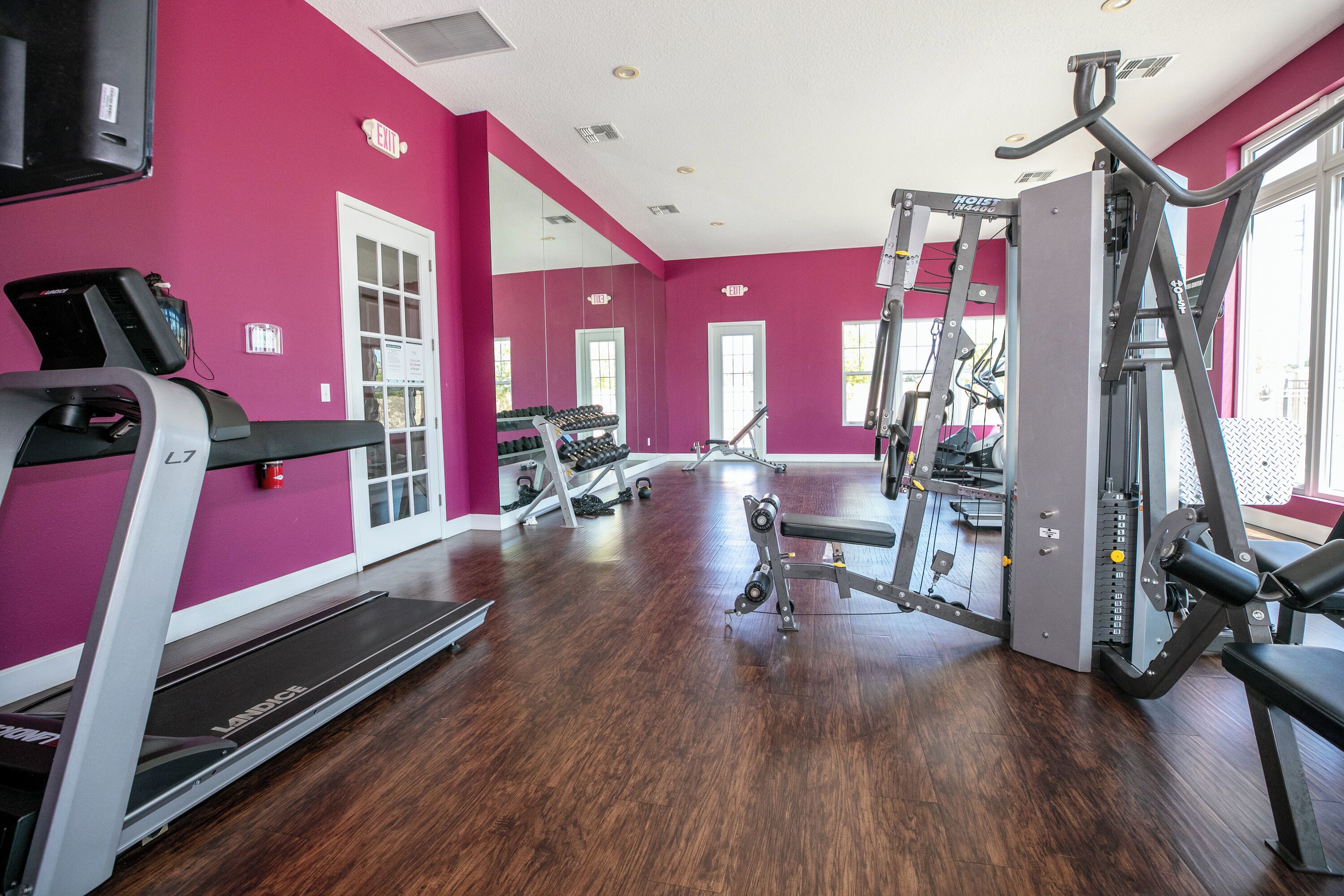 Et fitnesscenter med løbebånd, styrkemaskiner og et spejl.