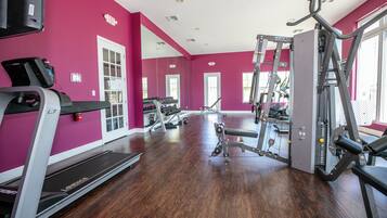 Un gimnasio con cintas de correr, máquinas de pesas y un espejo grande.