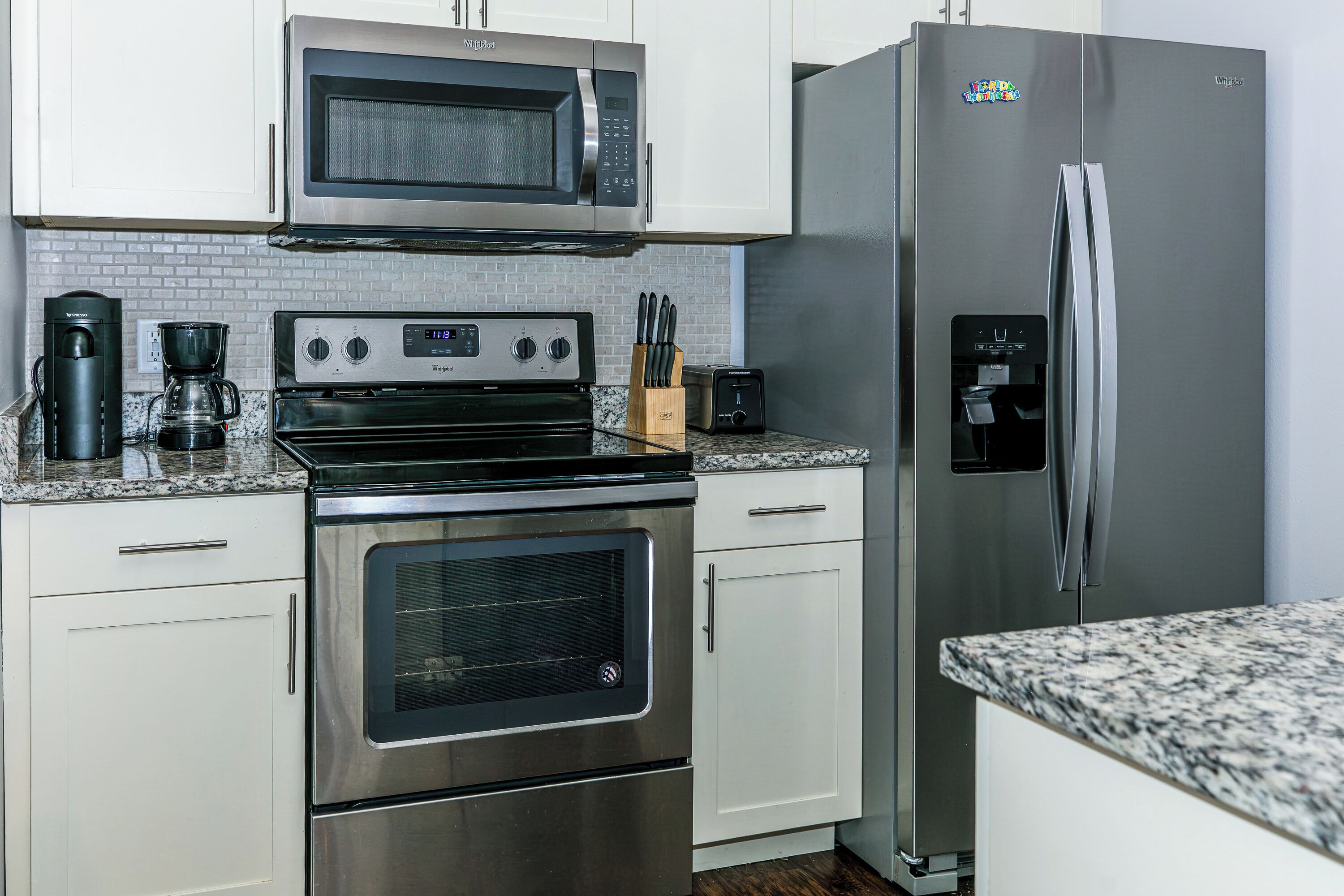 Una cocina con electrodomésticos de acero inoxidable, incluyendo un microondas, horno y refrigerador.