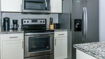 Una cocina con electrodomésticos de acero inoxidable, incluyendo un microondas, horno y refrigerador.