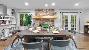 Un coin repas avec une table en bois dressée pour quatre personnes, entourée de chaises à revêtement gris.